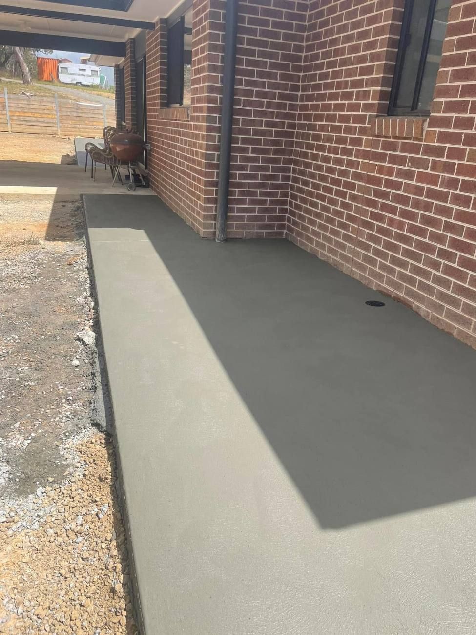 Wide concrete path beside a brick house